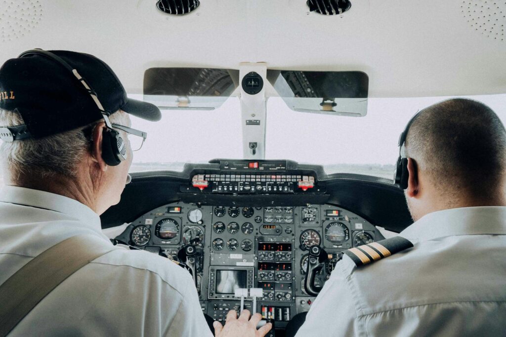 Close-up view of two pilots managing the cockpit controls of an aircraft, focusing on instrumentation.